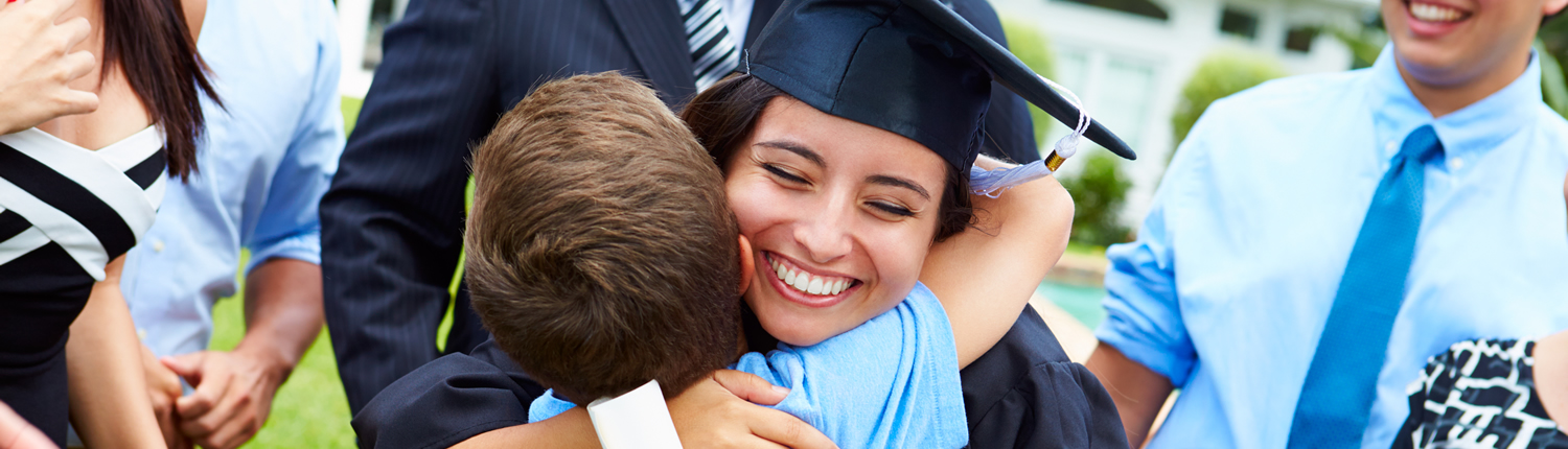 Image of a smiling woman in a cap and gown hugging a young child